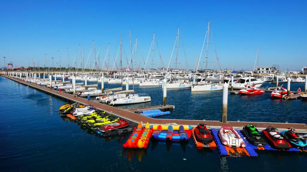 Jetskis and inflatable boats docked at the Dalian marina with yachts and sailboats in the background